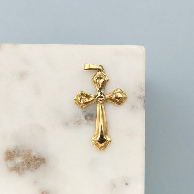 une image représentant une croix en or posée sur un bloc de marbre blanc