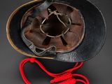 an old black hat with a red string around it on a black surface