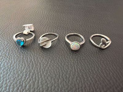 four rings with oplite stones on them sitting on top of a leather surface
