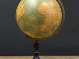 un vieux globe terrestre posé sur une table en bois, sur fond noir
