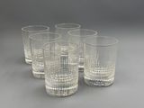 six verres à eau en verre transparent alignés sur une surface grise