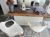 two white chairs sitting in front of a desk with a computer on top of it