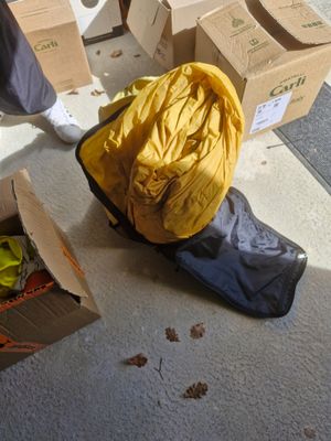 a person standing next to a box of clothes and a bag of luggage