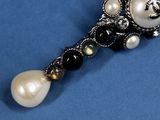 an image of a broochle with pearls and black and white beads