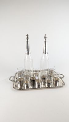 un plateau en argent sur lequel sont posées quatre bouteilles et un plateau en argent sur lequel sont posés deux salières et poivrières