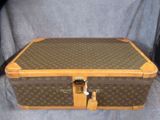 une valise marron et beige posée sur un tissu bleu