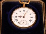 a small gold pocket watch with roman numerals in it