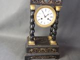 une horloge noire et dorée posée sur une table à côté d'une horloge dorée