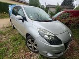 the silver car is parked on the grass in front of a house
