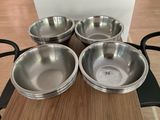 four stainless steel bowls sitting on top of a wooden table