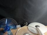 un ventilateur posé sur une table en bois, à côté d'un autre ventilateur