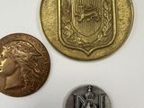 three different coins are shown on a white surface, one has a medal and the other has a medal