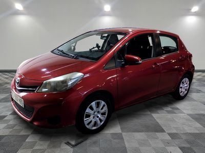the red toyota yaris is parked in a large room
