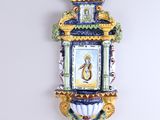 a wall clock with a painting on it on the wall