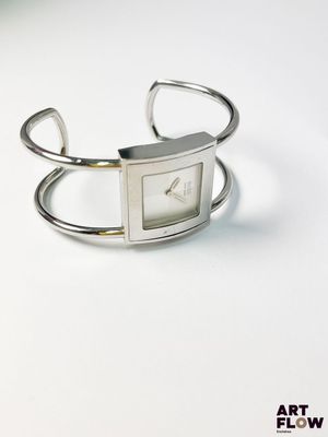 montre-bracelet en argent avec un cadran carré sur fond blanc