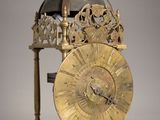 a gold clock on a stand on a gray background