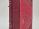 un vieux livre à la couverture rouge posé sur une surface blanche