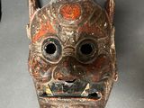 a wooden mask hanging on a wall next to a clock