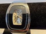 montre argentée et noire posée sur une surface à carreaux noirs et blancs