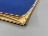 un livre bleu ouvert posé sur une table, à côté d'un stylo