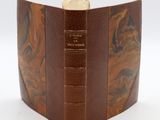 an old book with a leather cover and a gold coin in the middle