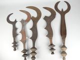 five wooden tools are lined up against a white wall