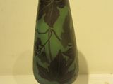 a green glass vase with a black base on a table