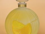 une image représentant un flacon de parfum jaune contenant une rondelle de citron