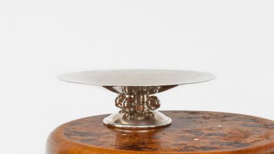 a silver plate on top of a wooden stand