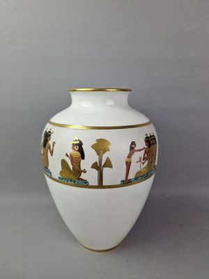 un vase blanc orné d'une bordure dorée et d'une illustration représentant des personnes
