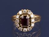 une image d'une bague avec une pierre rouge entourée de diamants blancs