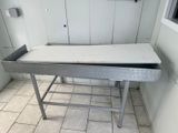 une table en métal avec un tiroir, dans une pièce