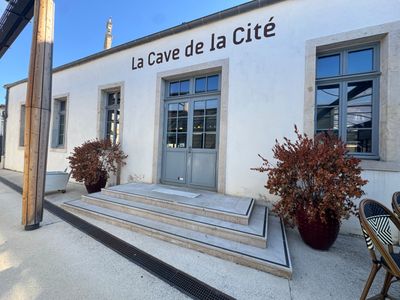 un bâtiment blanc avec une enseigne indiquant « La Cave de la Cité »
