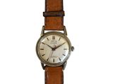 une vieille montre avec un bracelet en cuir marron sur fond blanc