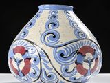 a blue and white vase with red flowers on it
