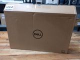 un ordinateur portable Dell posé sur une table en bois dans une pièce
