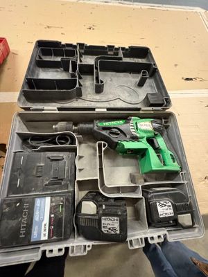 Quelqu'un tient une boîte à outils remplie d'outils posée sur une table.