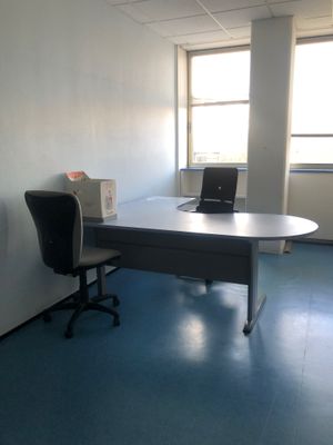 un bureau sur lequel se trouve un ordinateur, dans une pièce vide