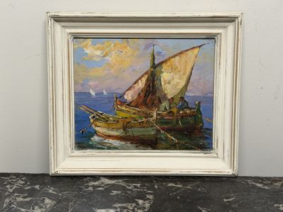 une peinture à l'huile représentant un voilier, dans un cadre blanc, posée sur une table