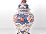 un vase bleu et blanc surmonté d'un oiseau