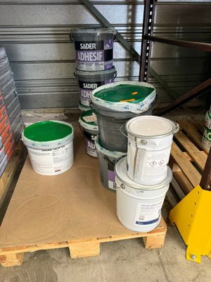 plusieurs seaux de peinture posés sur une palette dans un entrepôt