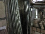 un tas de tuyaux métalliques dans une pièce, à côté d'un tas de bois