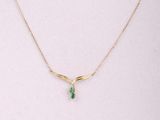 un collier en or orné d'une pierre verte autour du cou d'un mannequin