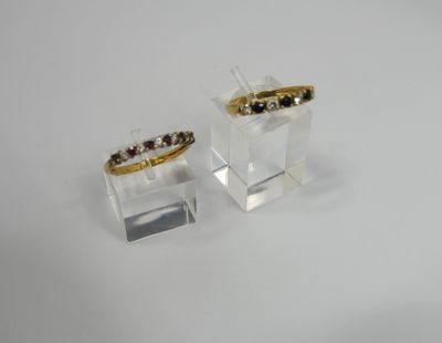 pair of gold and garnett rings on clear acrylic stand