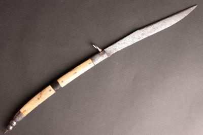 un couteau avec un manche en bois posé sur une surface noire