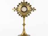 une horloge ancienne en laiton posée sur un socle, sur fond blanc