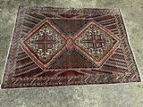 un vieux tapis orné d'un motif en forme de croix, posé sur un sol en béton