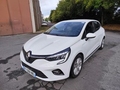 une voiture blanche garée dans un parking à côté d'un bâtiment