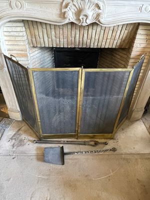 une cheminée avec une grille et une pelle devant