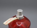 une bouteille en verre rouge avec un bouchon blanc et une étiquette dessus